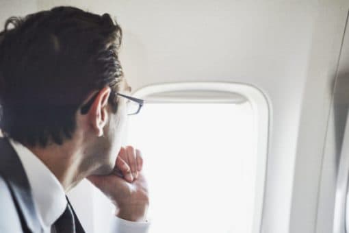 Man in suit looks out airplane window.
