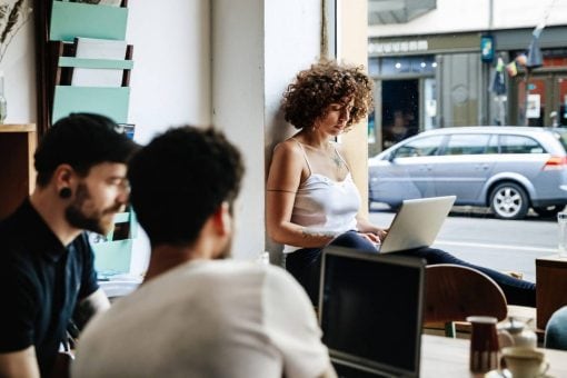 two men and a woman using laptops in a cafe