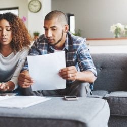 Young couple sits at home on their couch reviewing their credit scores.