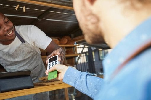 Customer inserts their credit card into a card reader at a bakery food cart