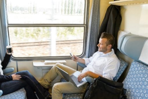 A couple sit across from one another on a train