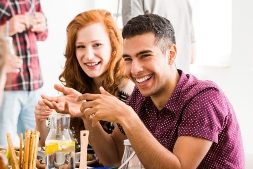 Man laughs as he sits with friends during meal.