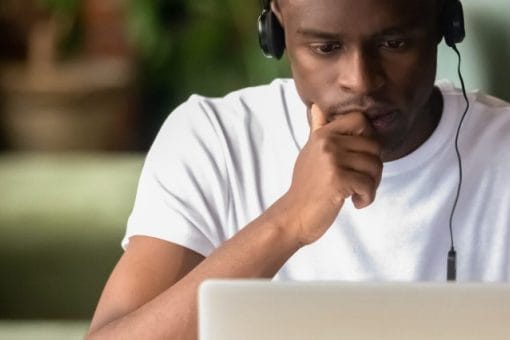 Man wearing headphones looks at laptop