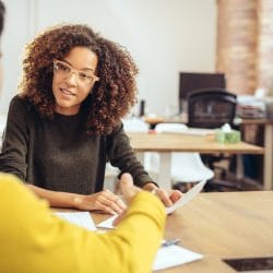 A woman and a man sit at a table talking about college gap year options.