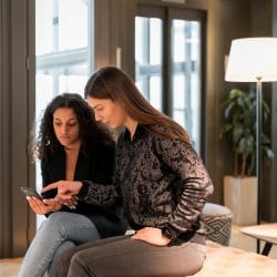 Two women looking down at a cellphone.