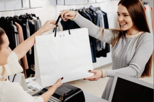 Happy woman takes a shopping bag from a cashier at a clothing store.