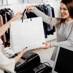 Happy woman takes a shopping bag from a cashier at a clothing store.