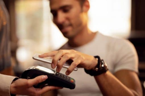 Man uses mobile phone to tap to pay on card reader