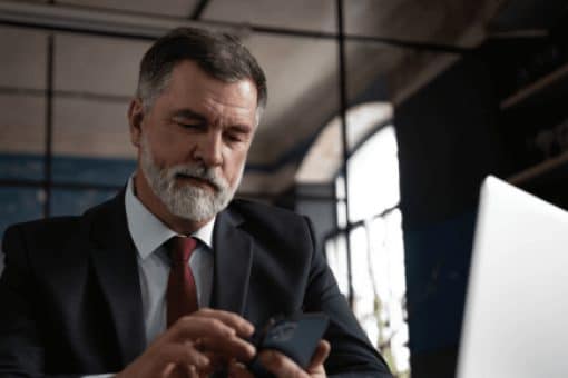 Businessman using mobile phone and laptop in office