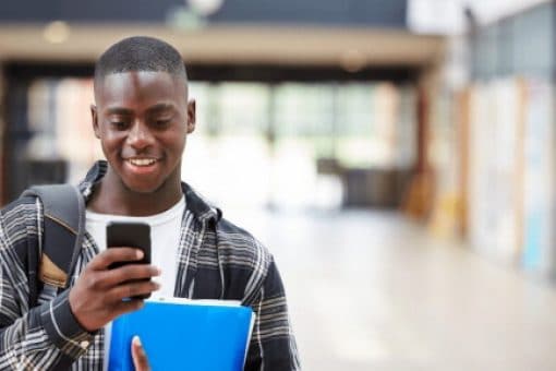 Male College Student Reading Text Message On Mobile Phone