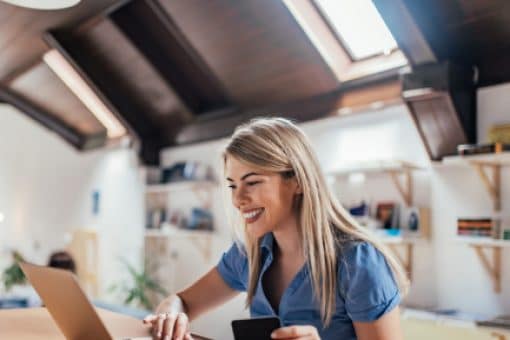 Young woman smiling at laptop with credit card in hand