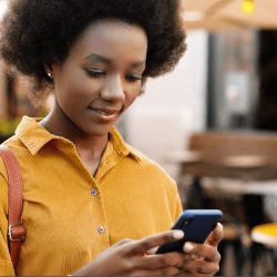 Woman standing outside of a restaurant looking at her phone.