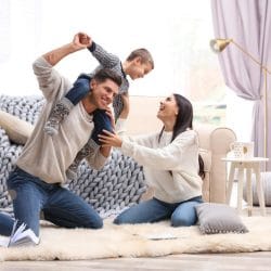 A man carries his son on his shoulder while his wife looks on.
