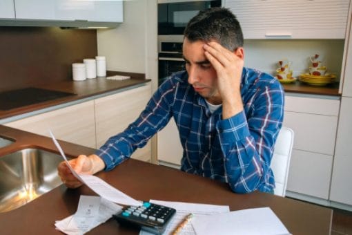 A worried man reviews his bills on his kitchen counter top.
