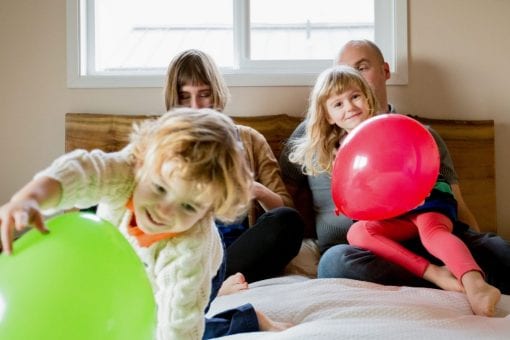 A family in a hotel with two young children playing with balloons.