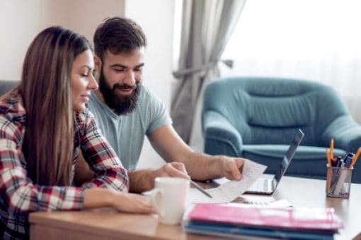 A couple reviews their finances at a coffee table.