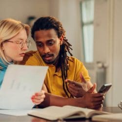 A man and a woman sit at a table reviewing their bills.