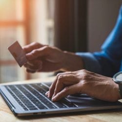 Close-up of hands typing on laptop and holding a credit card