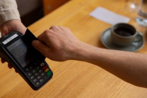 Hand swipes credit card through a credit card reader.