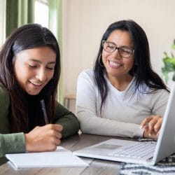 A mother helps her college aged daughter apply for a credit card.