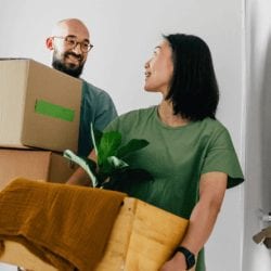 A man  and woman carry moving boxes.