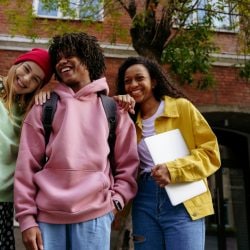 Three young students hang out on their college campus.