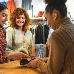 A woman uses her digital wallet to make a purchase at a clothing boutique.