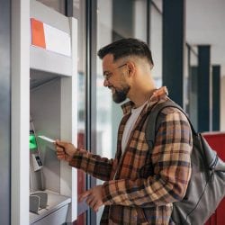 A person uses a credit card at an ATM.