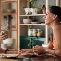 Two women sit together talking in a cafe.