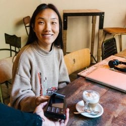 Cheerful woman paying for coffee with credit card