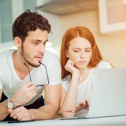 A couple sits together looking at a laptop computer.