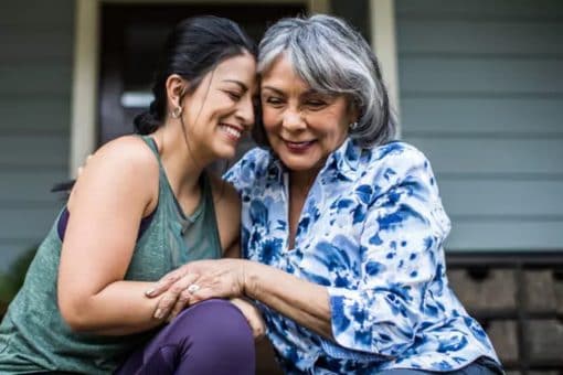 Senior woman and adult daughter laughing on porch