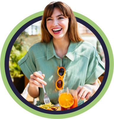 Woman in linen shirt smiling and eating breakfast on sunny patio