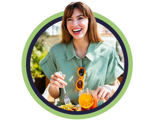 Woman in linen shirt smiling and eating breakfast on sunny patio