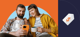 A man and woman sitting together each holding a mug while looking at the man's phone