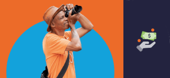 A man wearing a hat puts a camera to his eye to take a photo
