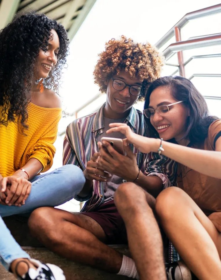 A man and a woman check a phone while another woman watches