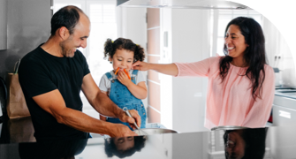 Parents with their young child in the kitchen, all smiling and interacting