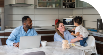 Parents sitting at a table with their young child in a modern kitchen, interacting and smiling