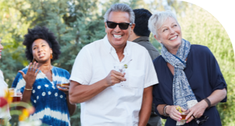 Group of people enjoying an outdoor gathering, with a man in sunglasses and a woman smiling in the foreground