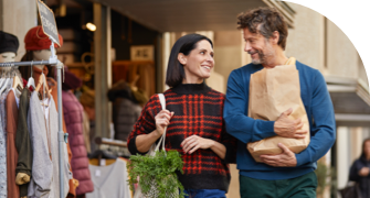 A couple smiling and walking with shopping bags outside a clothing store