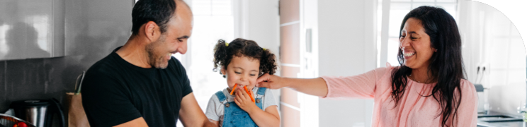 Parents with their young child in the kitchen, all smiling and interacting
