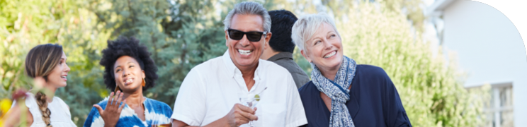 Group of people enjoying an outdoor gathering, with a man in sunglasses and a woman smiling in the foreground