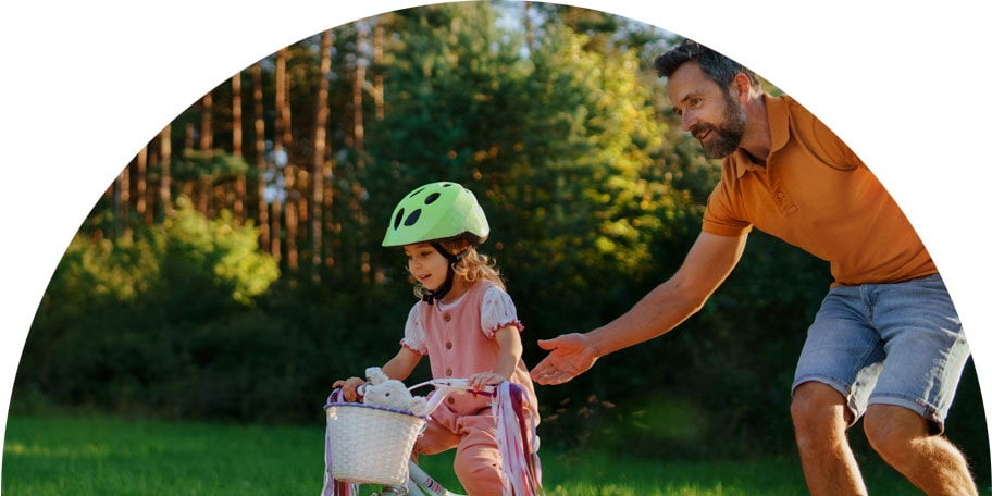 Image of a father helping daughter learn to ride a bike