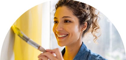 Image of a woman painting a wall with a brush