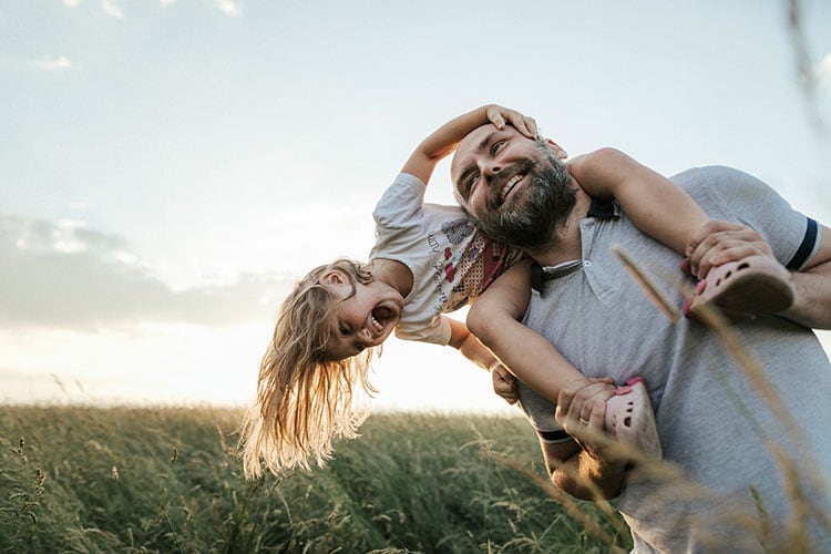 Man with daughter on his shoulders, playing outside