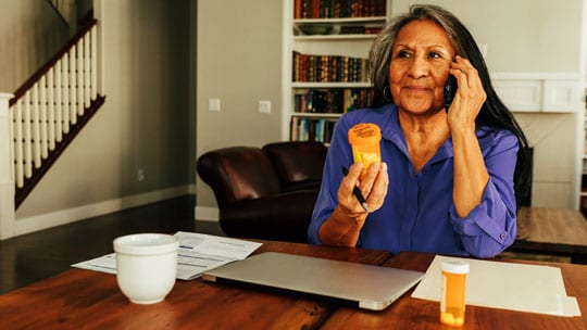 Woman on the phone holding a prescription bottle.