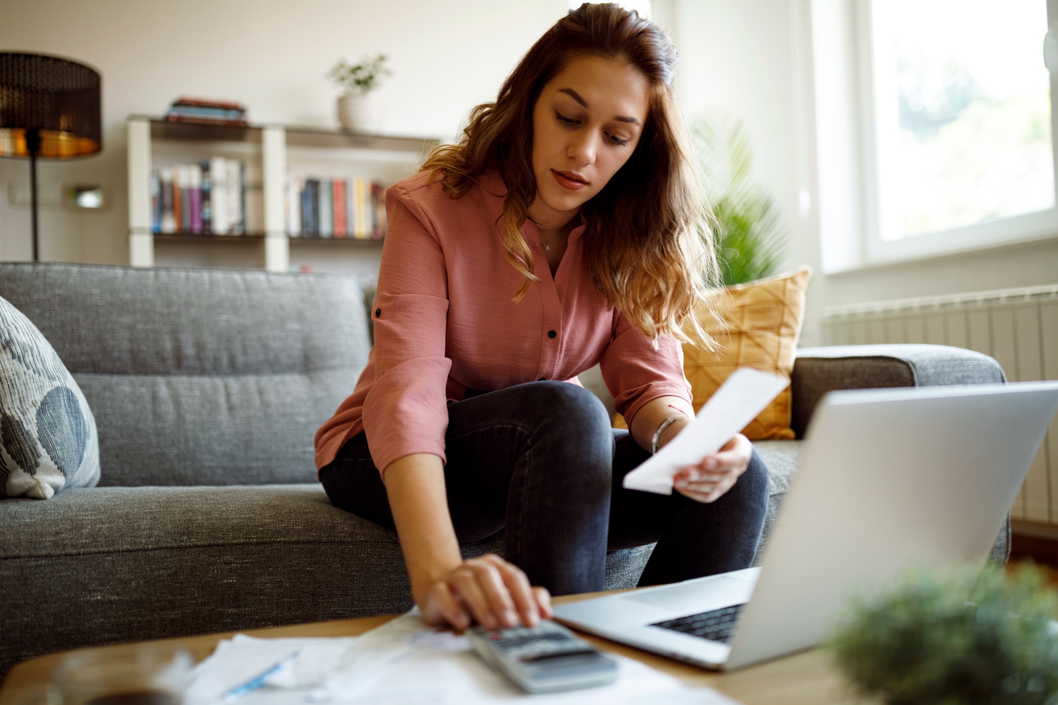 Image of a woman working on her finances with a calculator and computer