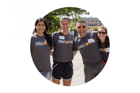Four Green Team members standing together wearing matching Discover tee shirts, smiling and posing for a picture.