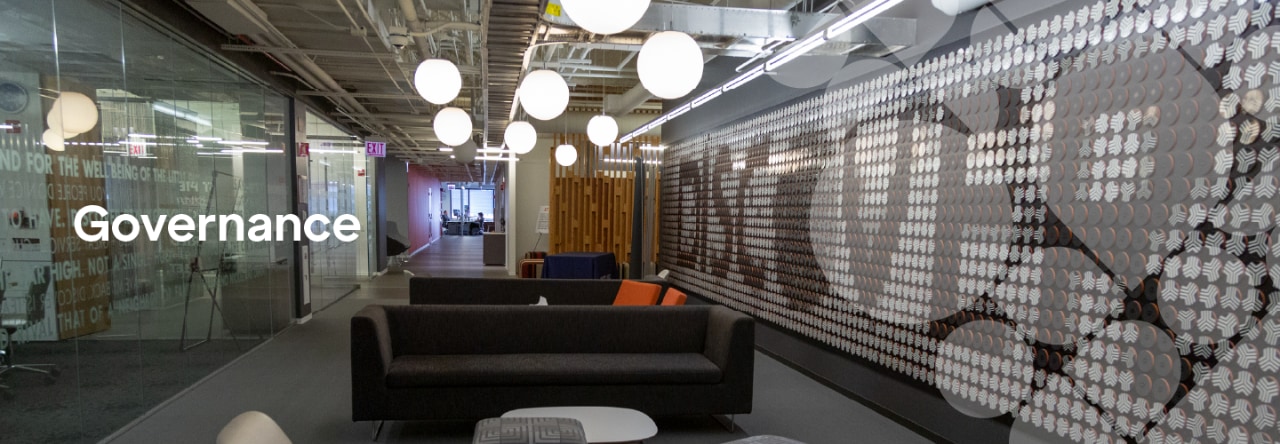 Interior of Discover office building, showing a wide walkway featuring several dark blue couches and large orb-shaped overhead lights.